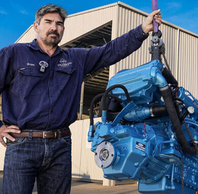 Brian Trautman of SV Delos stands next to a NANNI diesel engine and sailing yacht Delos 1.0 on the hardstand